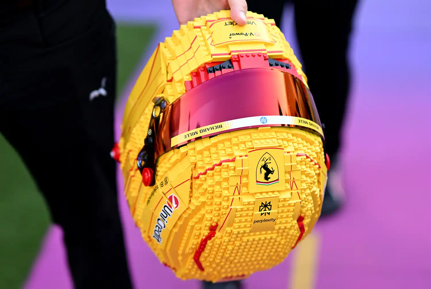 Close-up top view of the yellow LEGO Ferrari helmet showing the Ferrari logo and brick texture.