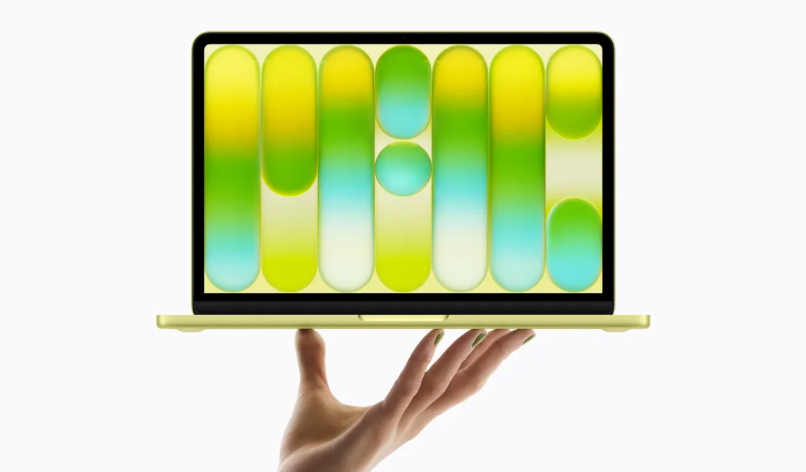 Front view of citrus MacBook Neo held aloft by a single hand.