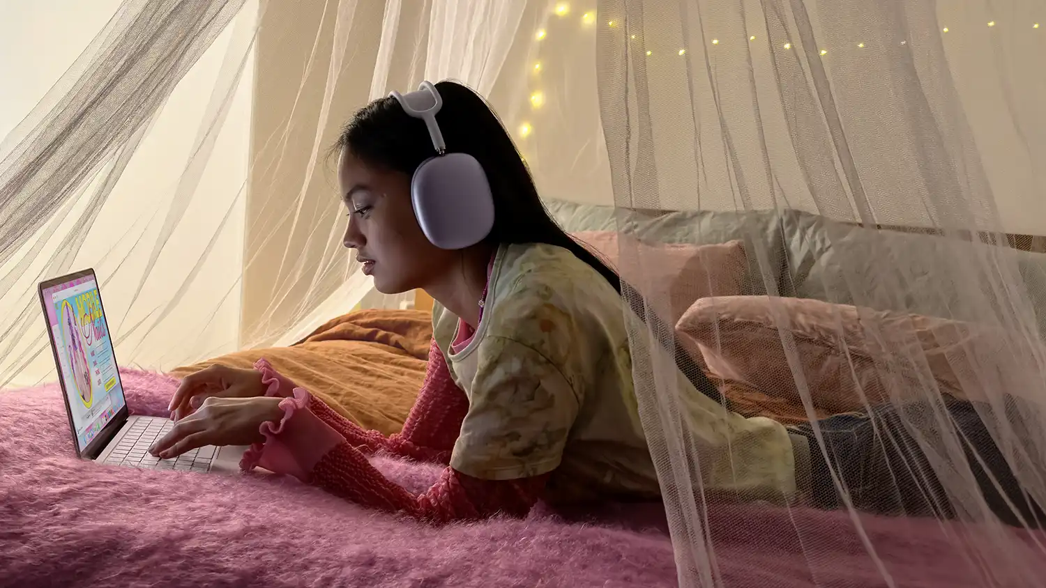 A person using a MacBook Neo while lounging with AirPods Max.