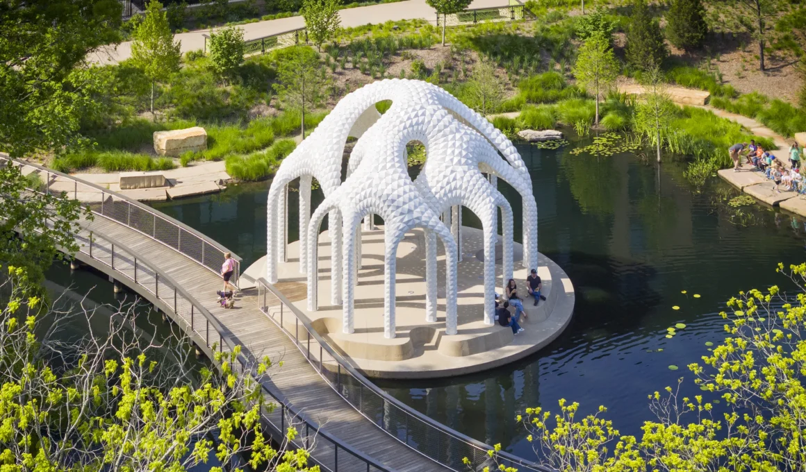 Wide angle view of L’île Folie pavilion on a circular island in Downtown Cary Park with visitors.