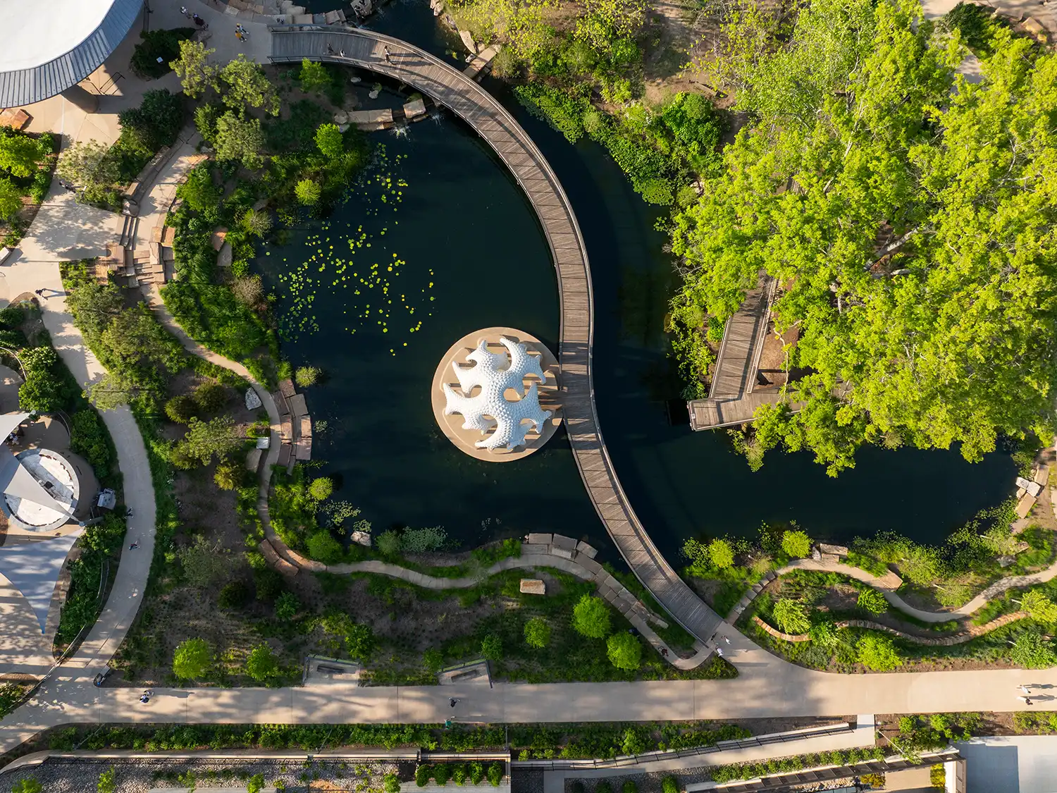 Top-down aerial drone shot of L’île Folie pavilion and curved walkway in Cary North Carolina park.