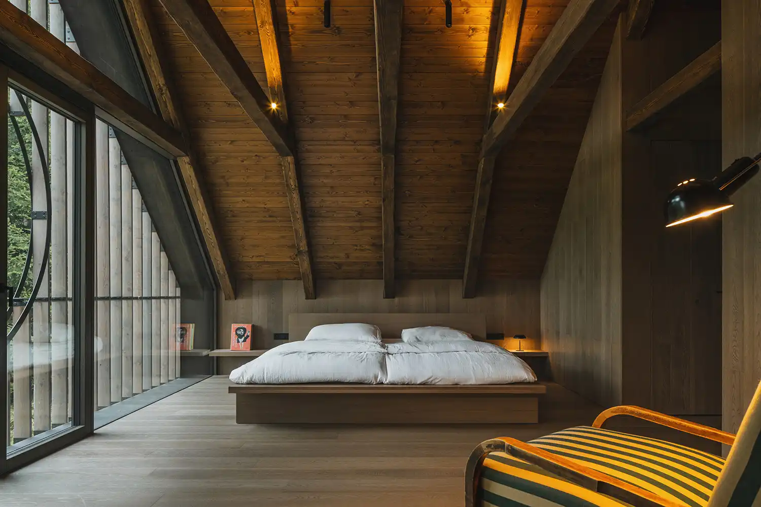 Master bedroom in the attic with exposed timber rafters and large floor-to-ceiling windows.