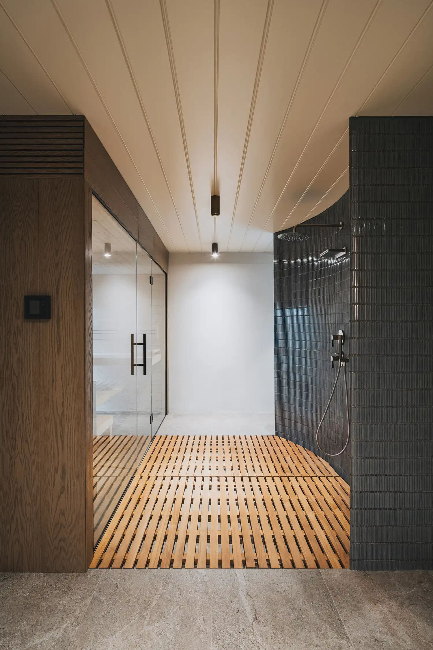 Modern spa area with a glass-walled sauna, wooden slat flooring, and curved tile shower.