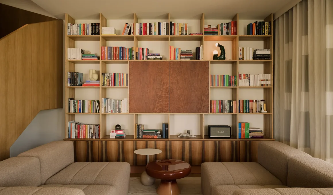 Custom walnut and ash bookcase in a contemporary living room with neutral modular sofas.