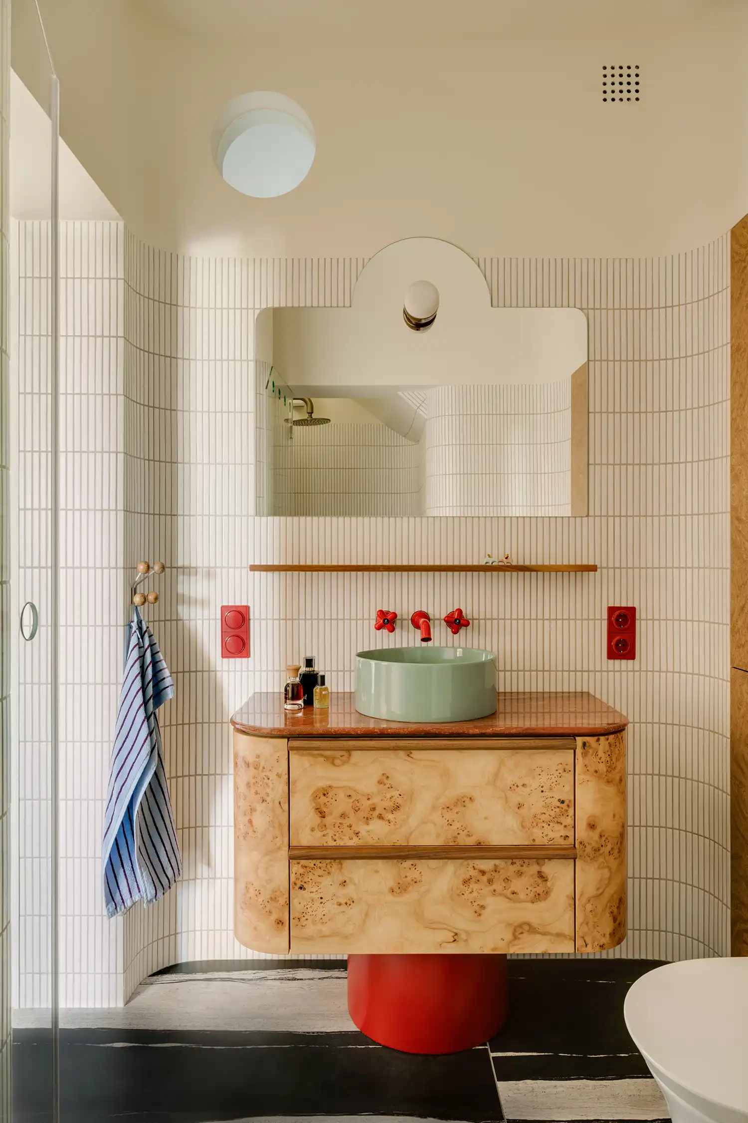 Bold bathroom design with burr wood vanity, red travertine top, and cobalt blue washbasin.