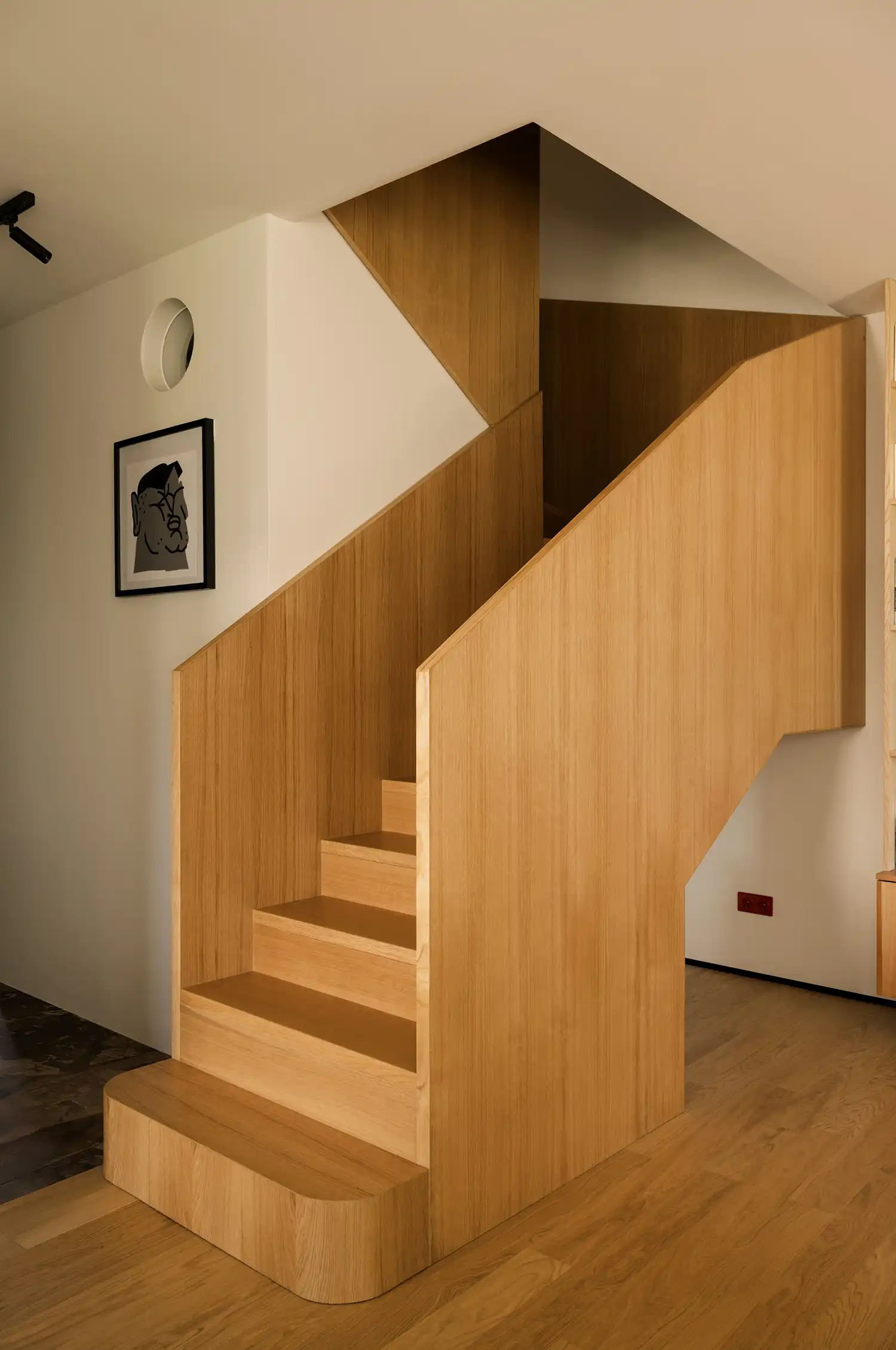 Modern oak staircase with geometric solid balustrades in a minimalist Kraków home.