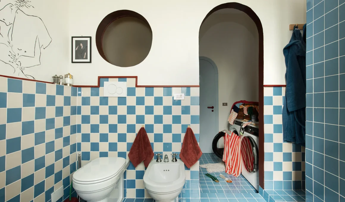 Close-up of a minimalist white flush plate for a concealed cistern in a modern tiled bathroom.