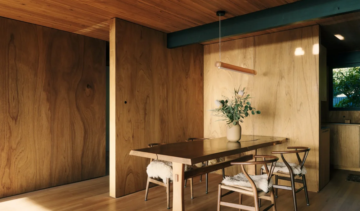 Dining area with wood-paneled walls, mahogany table, and Hans Wegner Wishbone chairs.