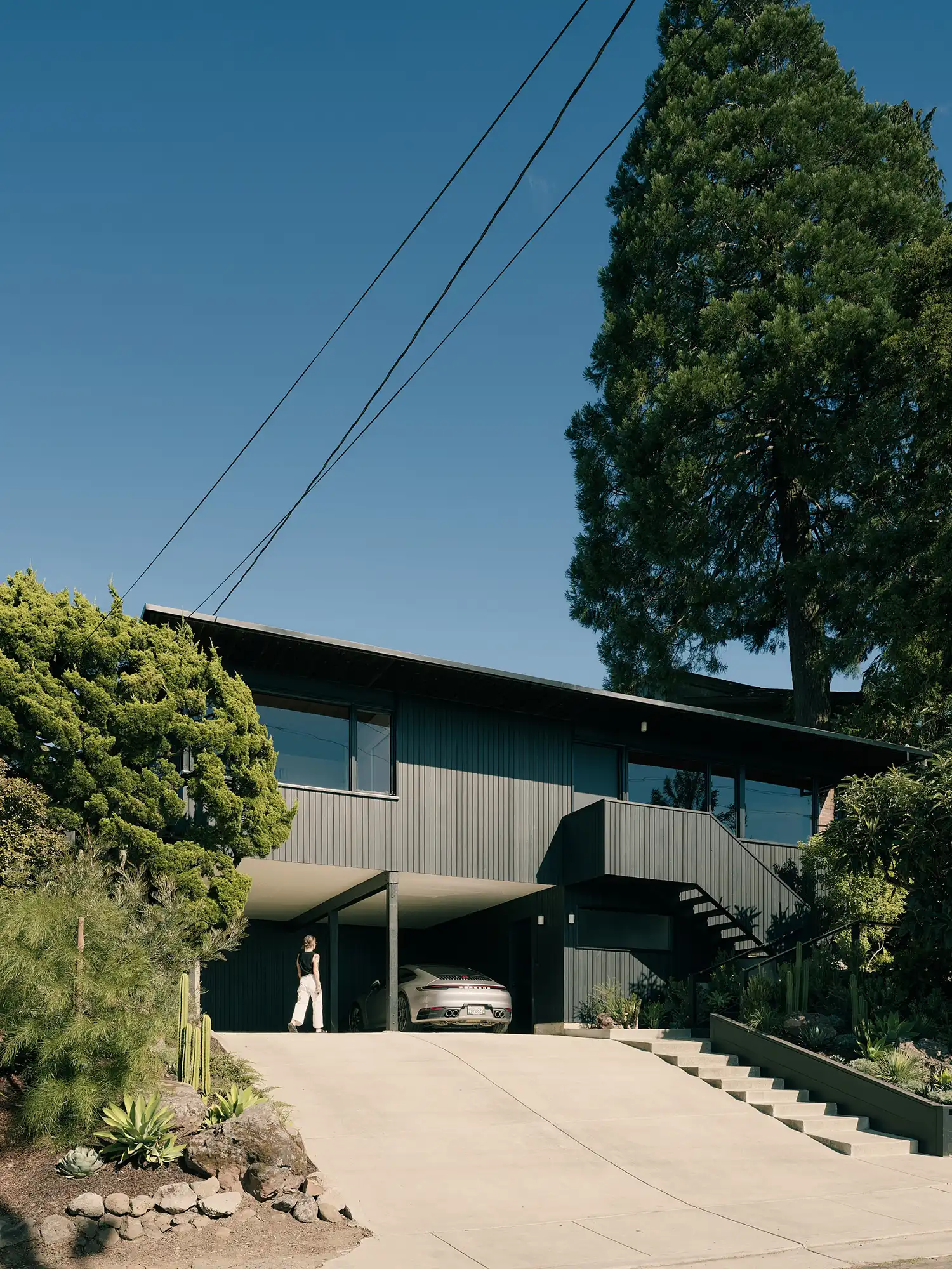 Exterior view of the dark-stained wood Creston House with a car parked in the carport.