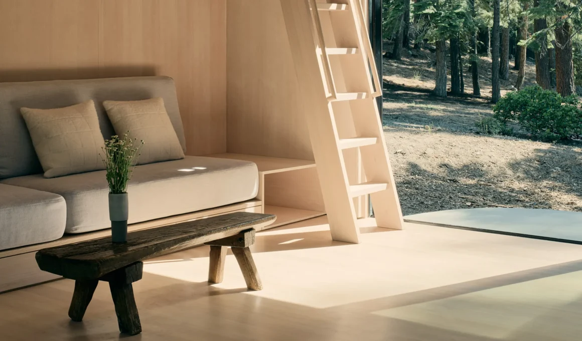Detail shot of a plywood ladder leading to a mezzanine home office next to a floor-to-ceiling glass door.