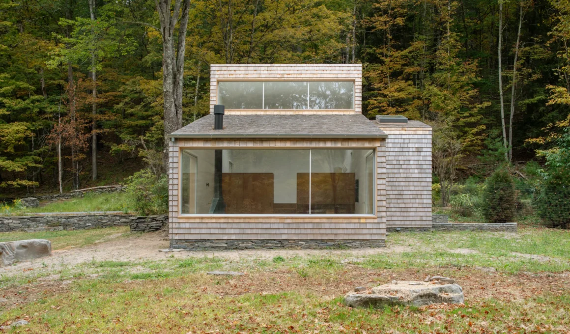 Exterior of a shingle-clad house in New York with large panoramic windows and clerestory glazing.
