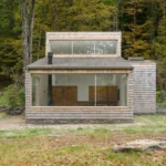 Exterior of a shingle-clad house in New York with large panoramic windows and clerestory glazing.