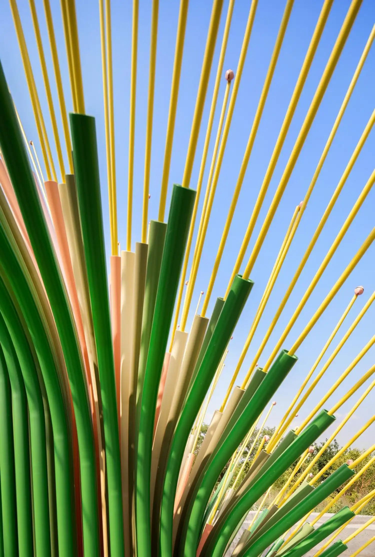 Close-up detail of green and pink powder-coated steel tubes and the yellow rods sprouting from them.