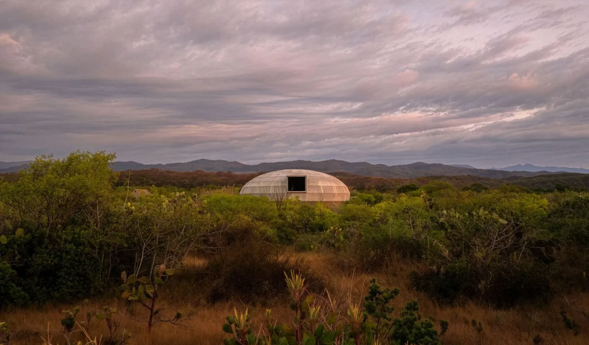 External view of the dome-shaped concrete pavilion at twilight in Oaxaca