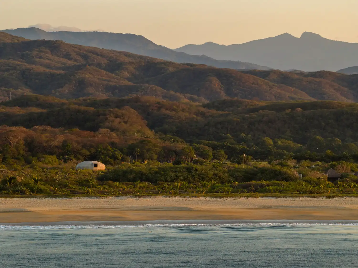 Aerial coastal view of the Mushroom Pavilion between the mountains and the Pacific Ocean