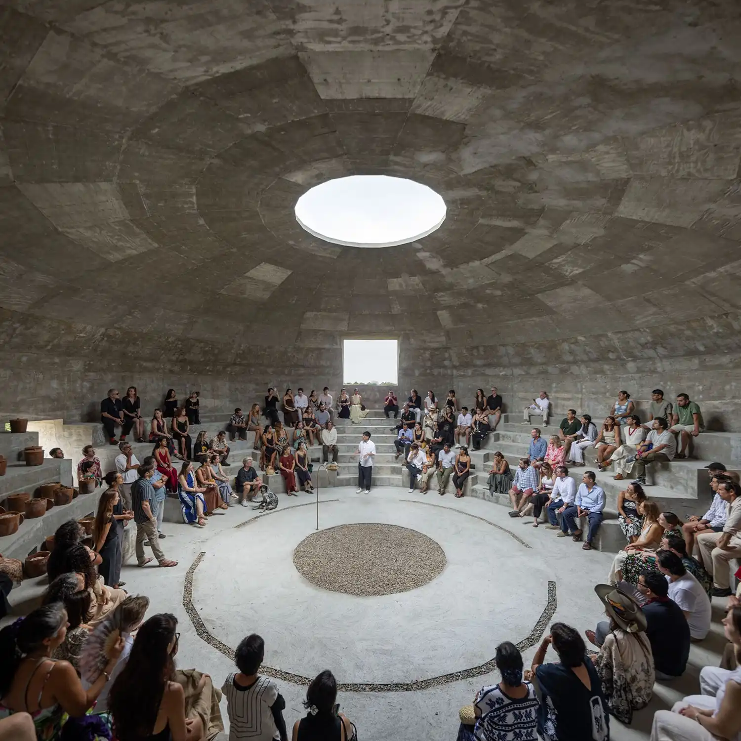 Interior view of a large group of people seated on the pavilion's concrete tiers