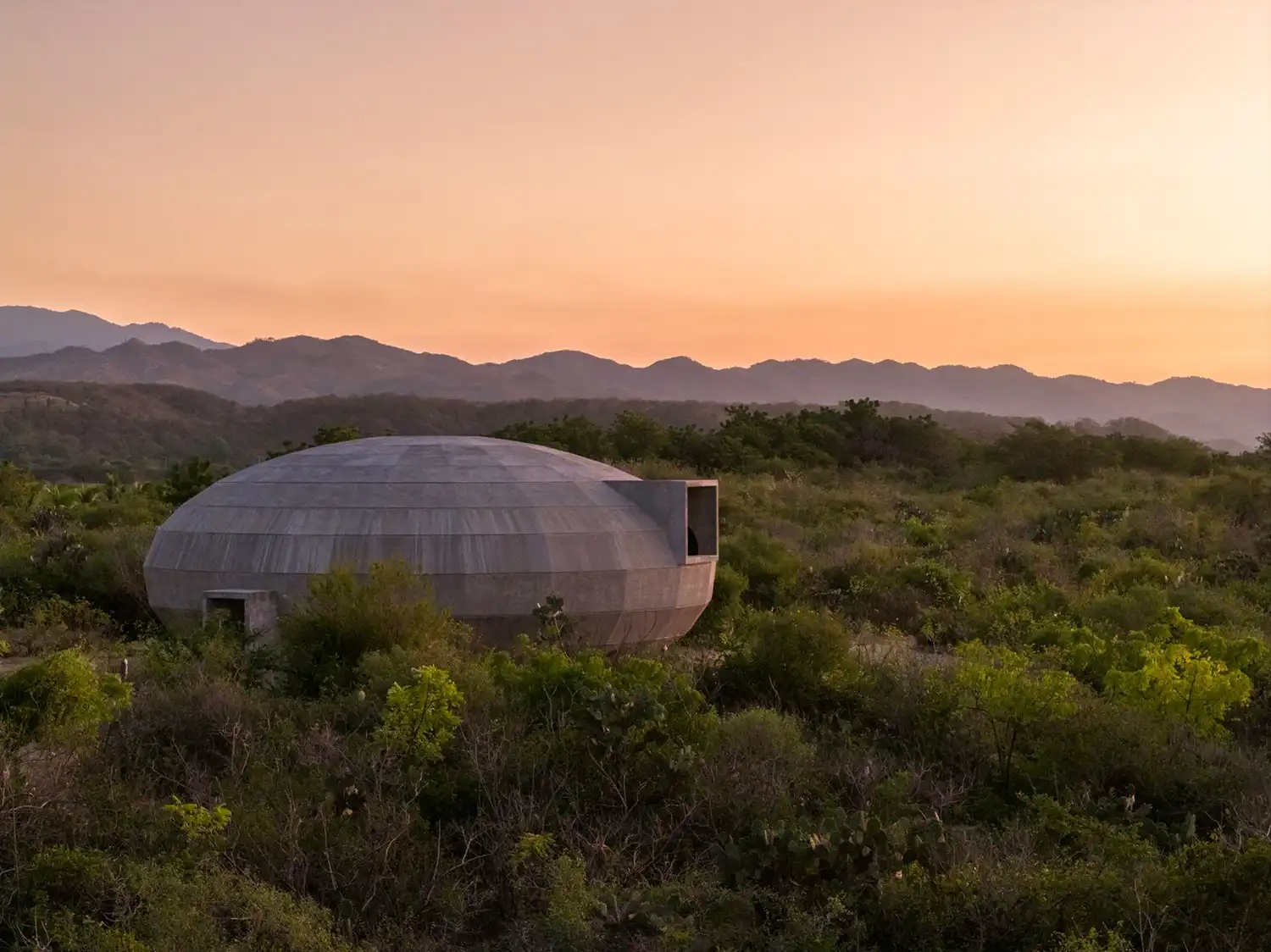 Side view of the concrete pavilion exterior during a golden hour sunset