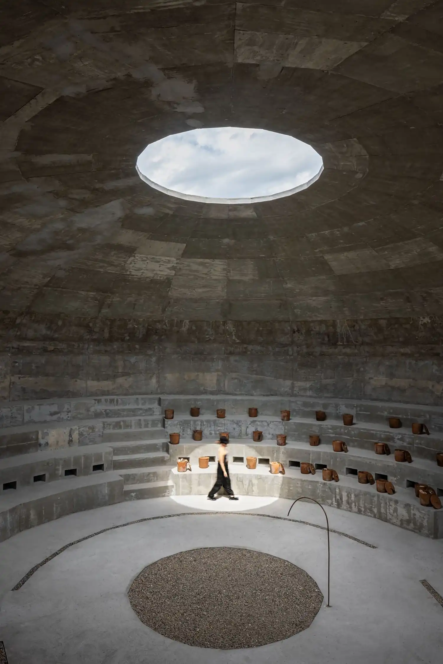 A person walking through a beam of light inside the tiered concrete pavilion