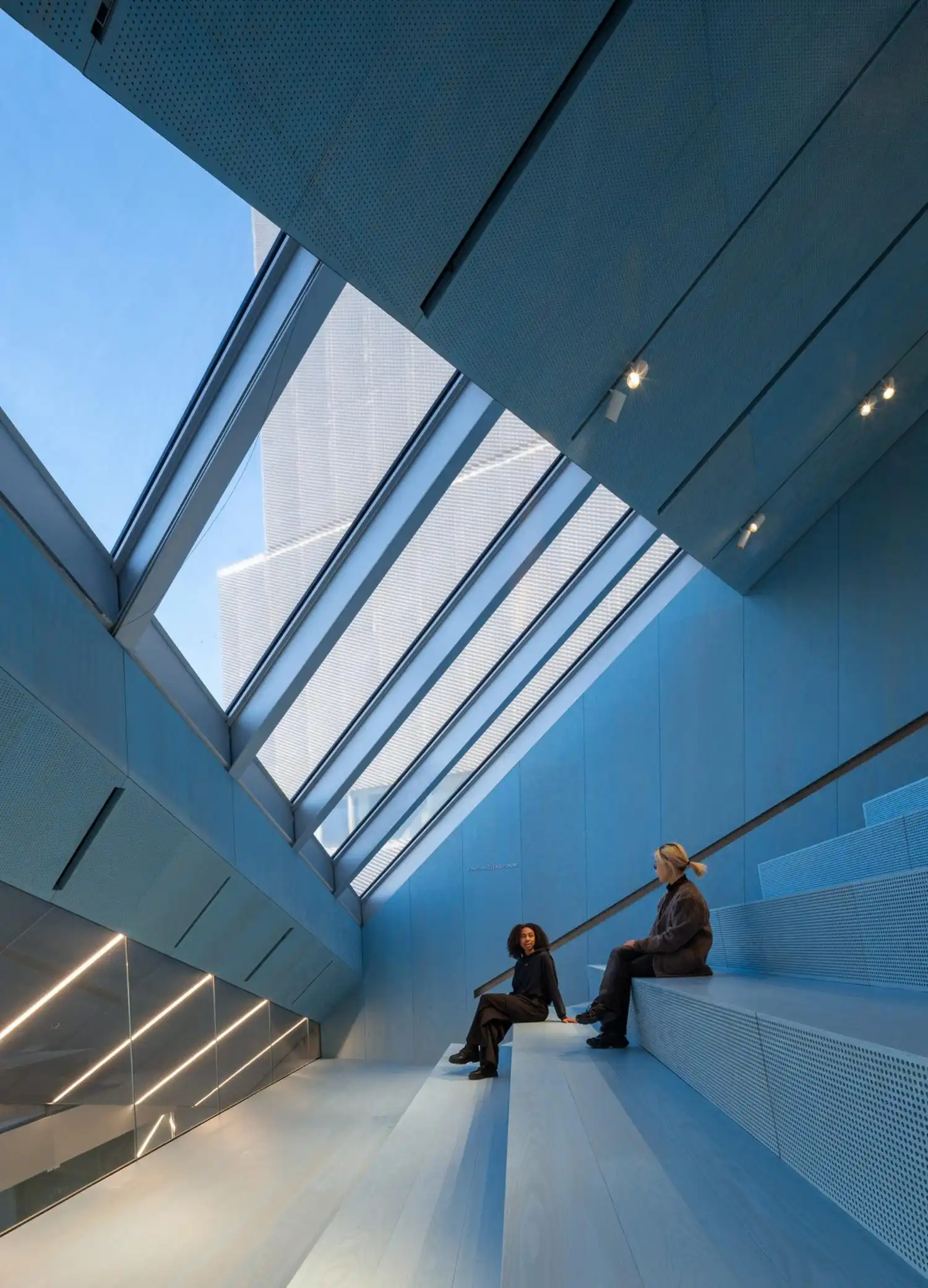 Blue-toned interior of the museum auditorium with large windows overlooking the city.