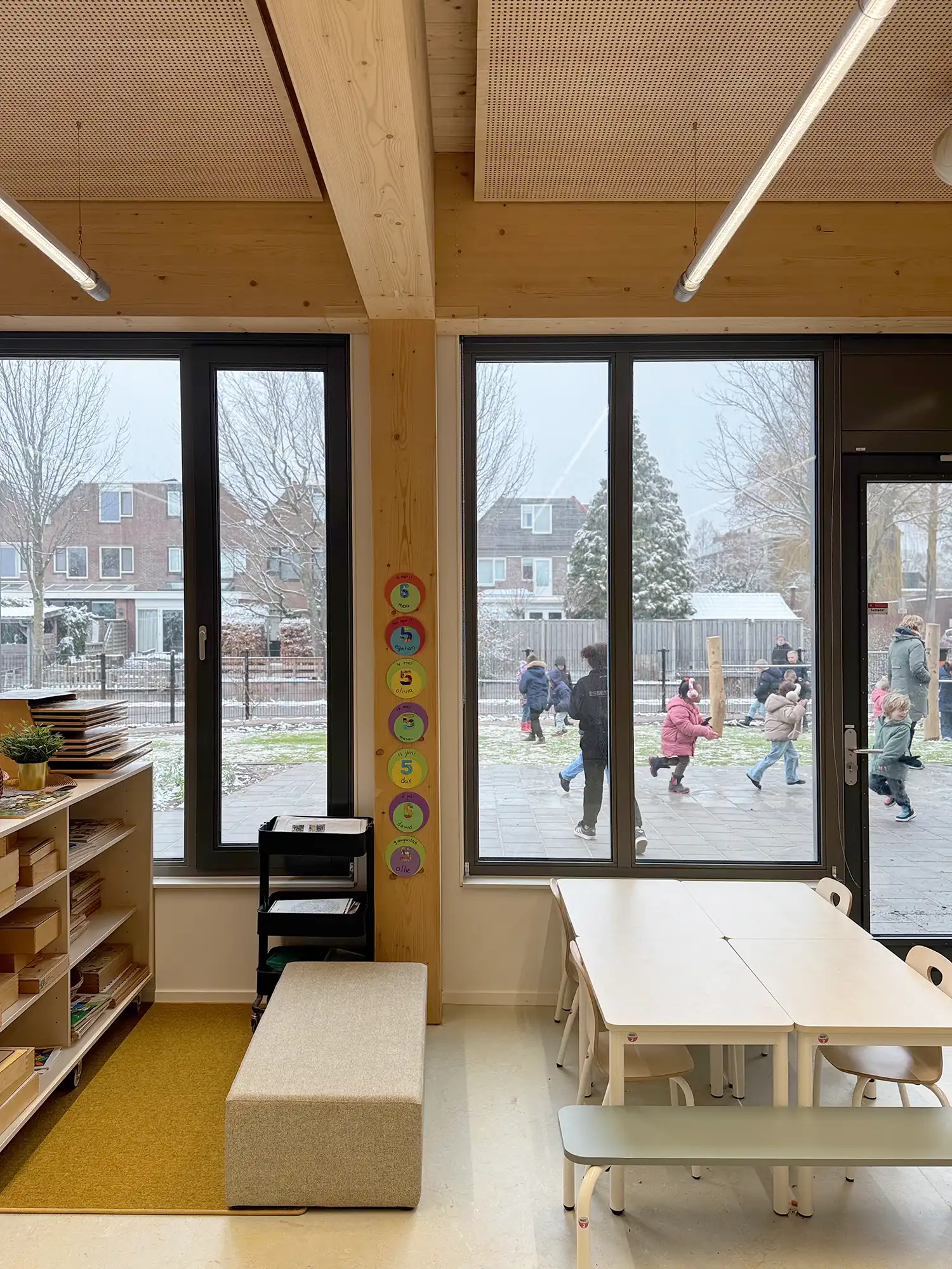 Wide French doors and a glazed facade connect a minimalist classroom directly to the snowy outdoor playground at Wisperweide.