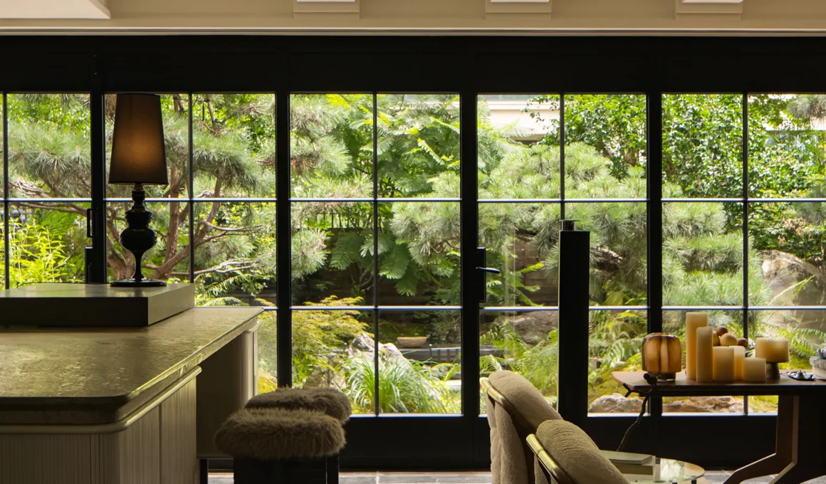 The transition between the living area and the garden is softened by expansive black-framed glass walls.