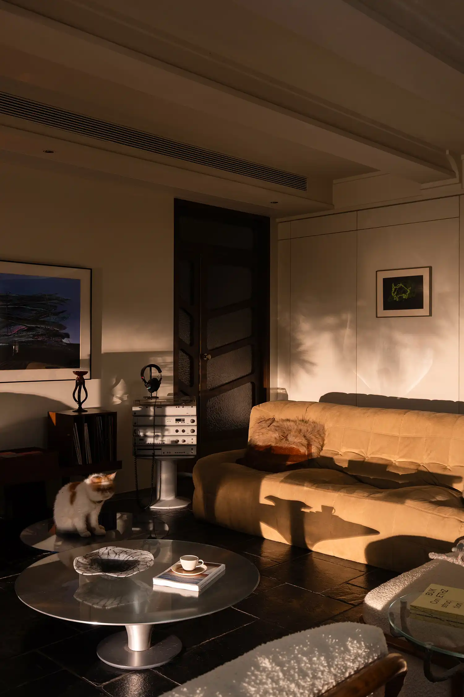 Warm light filters through the interior, casting dramatic shadows across the relaxed seating area.