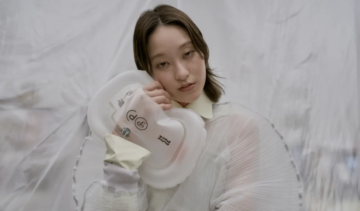 A person holding the translucent Pulse Pack bag against their cheek, showing its soft, inflatable texture and integrated electronic sensors.