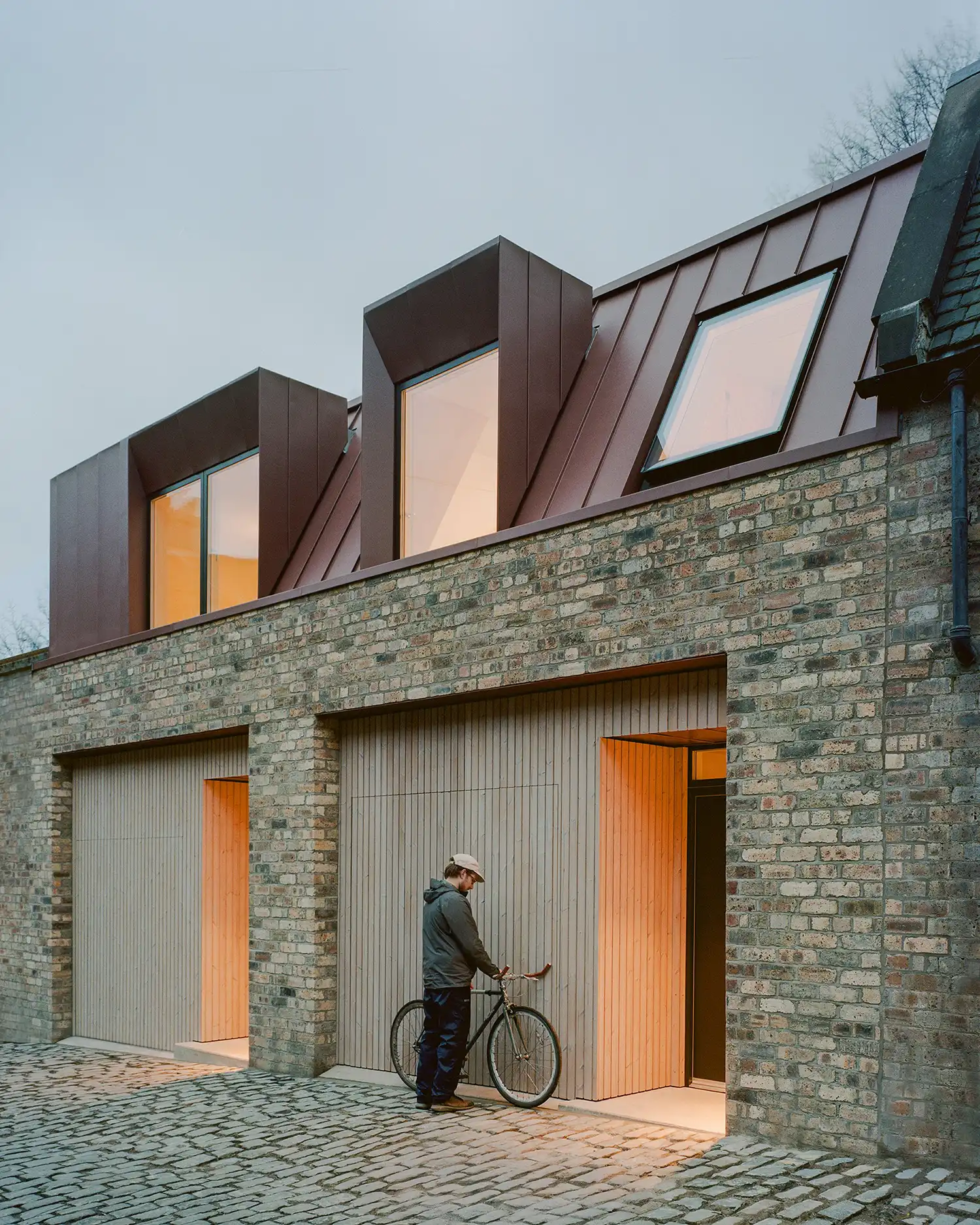 Bedroom with olive green bedding and a large window facing an old stone wall.