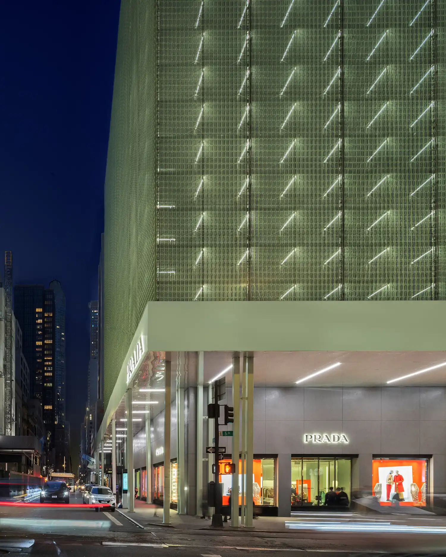 Night view of the Prada Fifth Avenue store, featuring the integrated internal lighting that transforms the green scaffold into a glowing lantern.