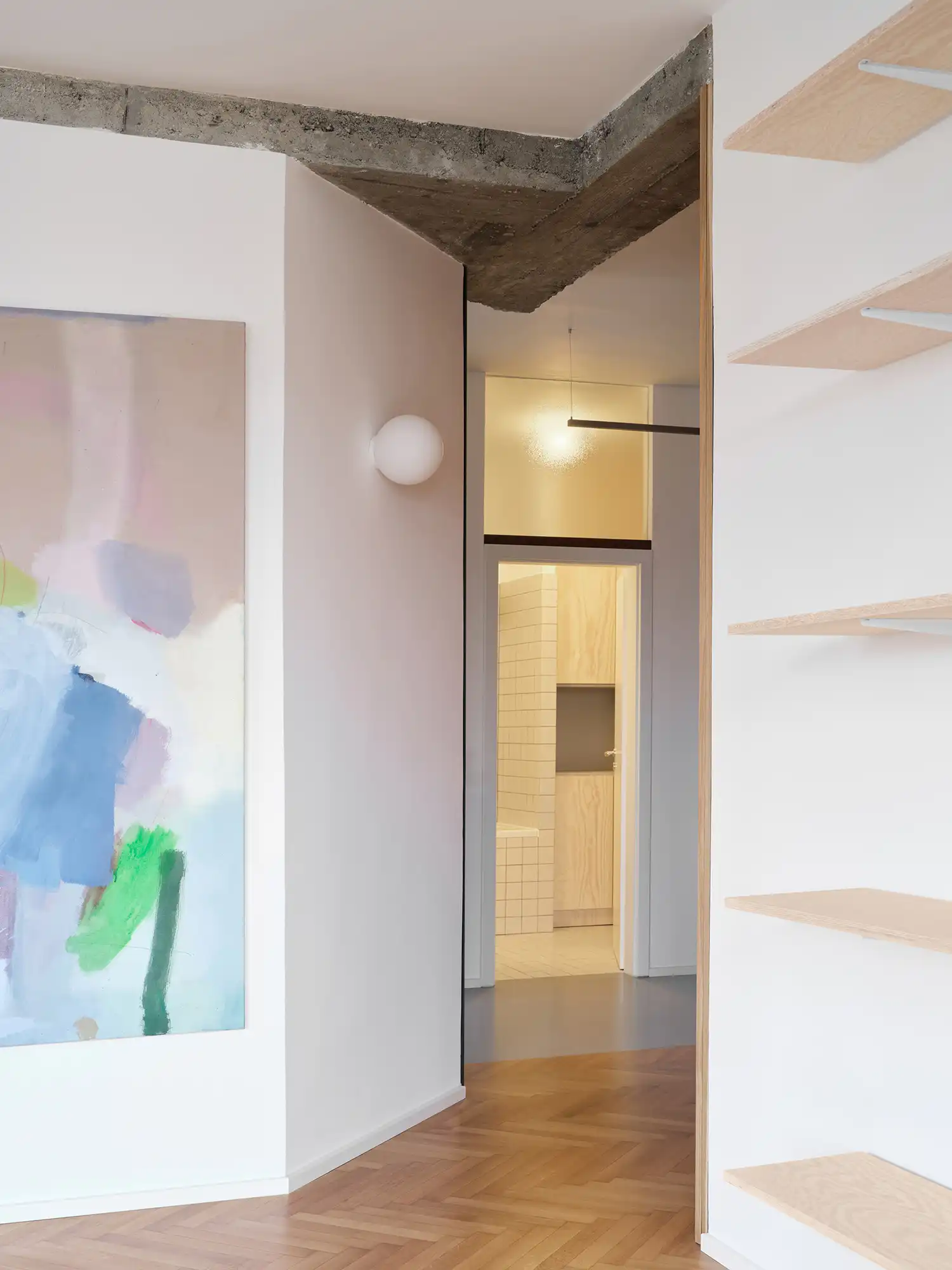 A view from the living area through a doorway into a white-tiled bathroom with a glass block partition.