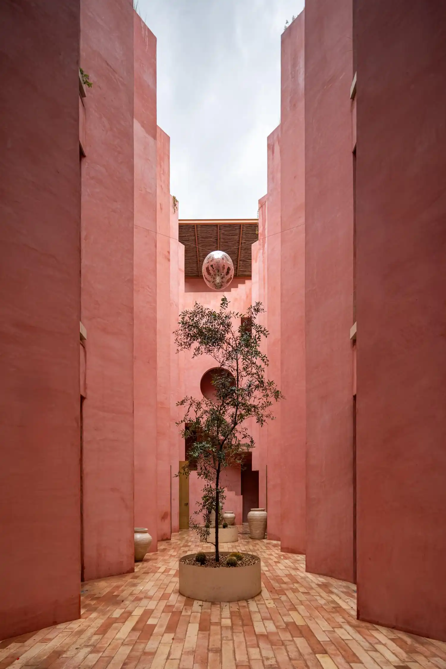Interior vertical courtyard with a central tree and a disco ball hanging above.