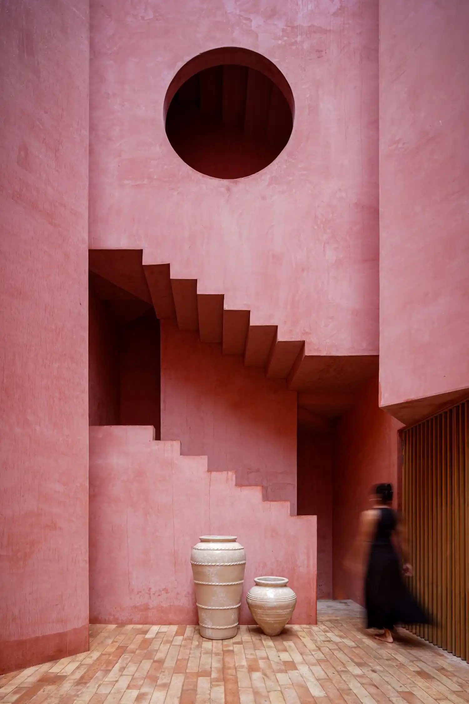 Pink stucco staircase in the central courtyard with a circular void.