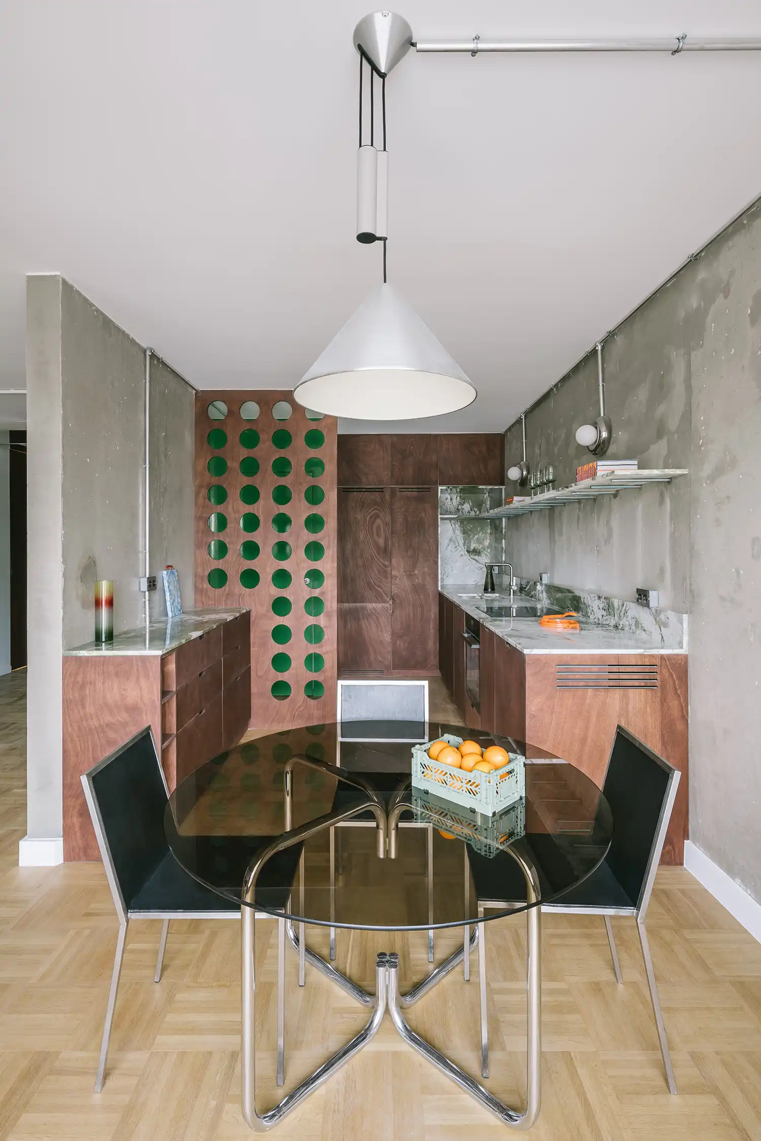 Modern kitchen and dining area with dark wood cabinetry, marble countertops, and a glass-top dining table.