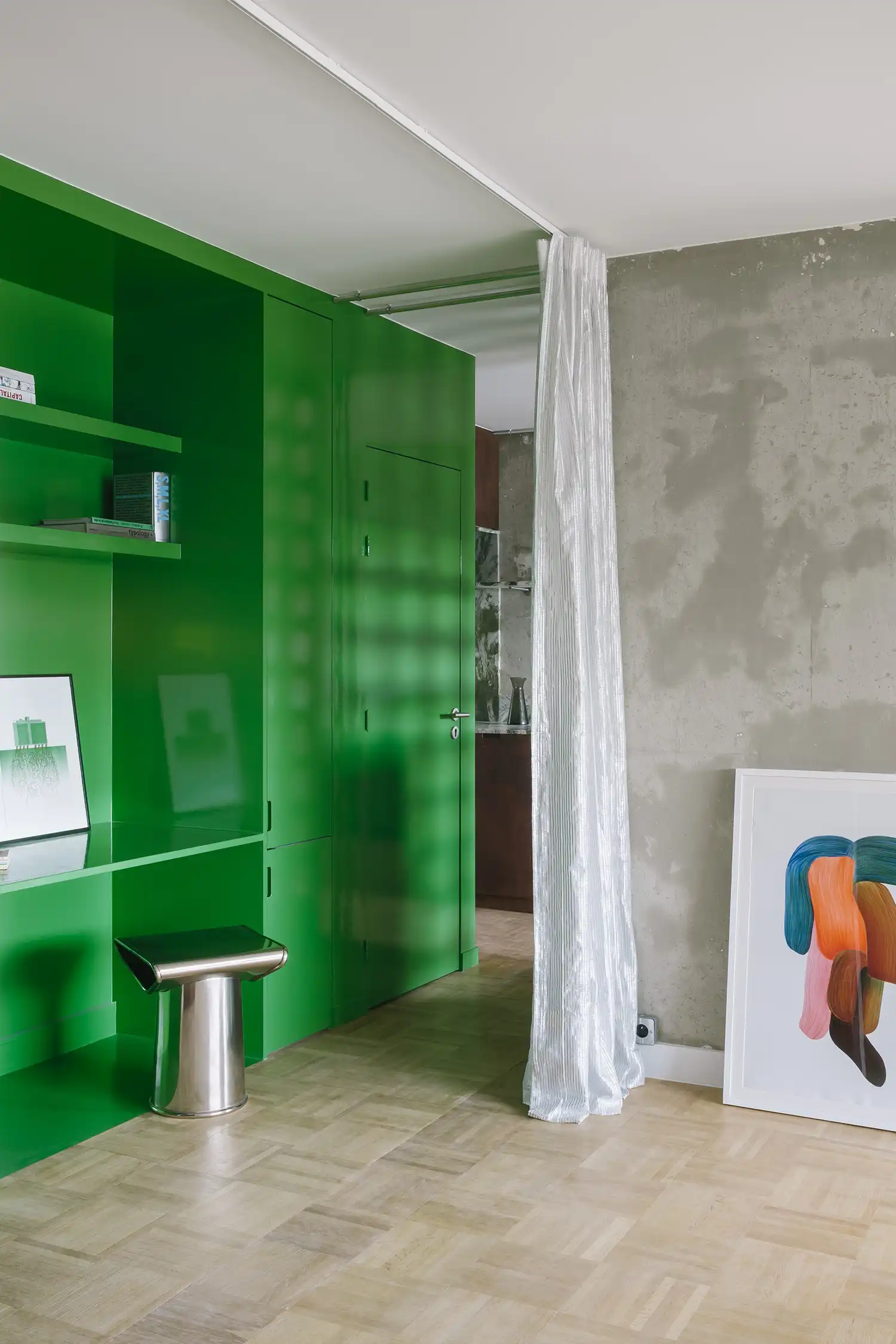 Close-up of a vibrant green lacquered storage unit and desk area next to a translucent white curtain.
