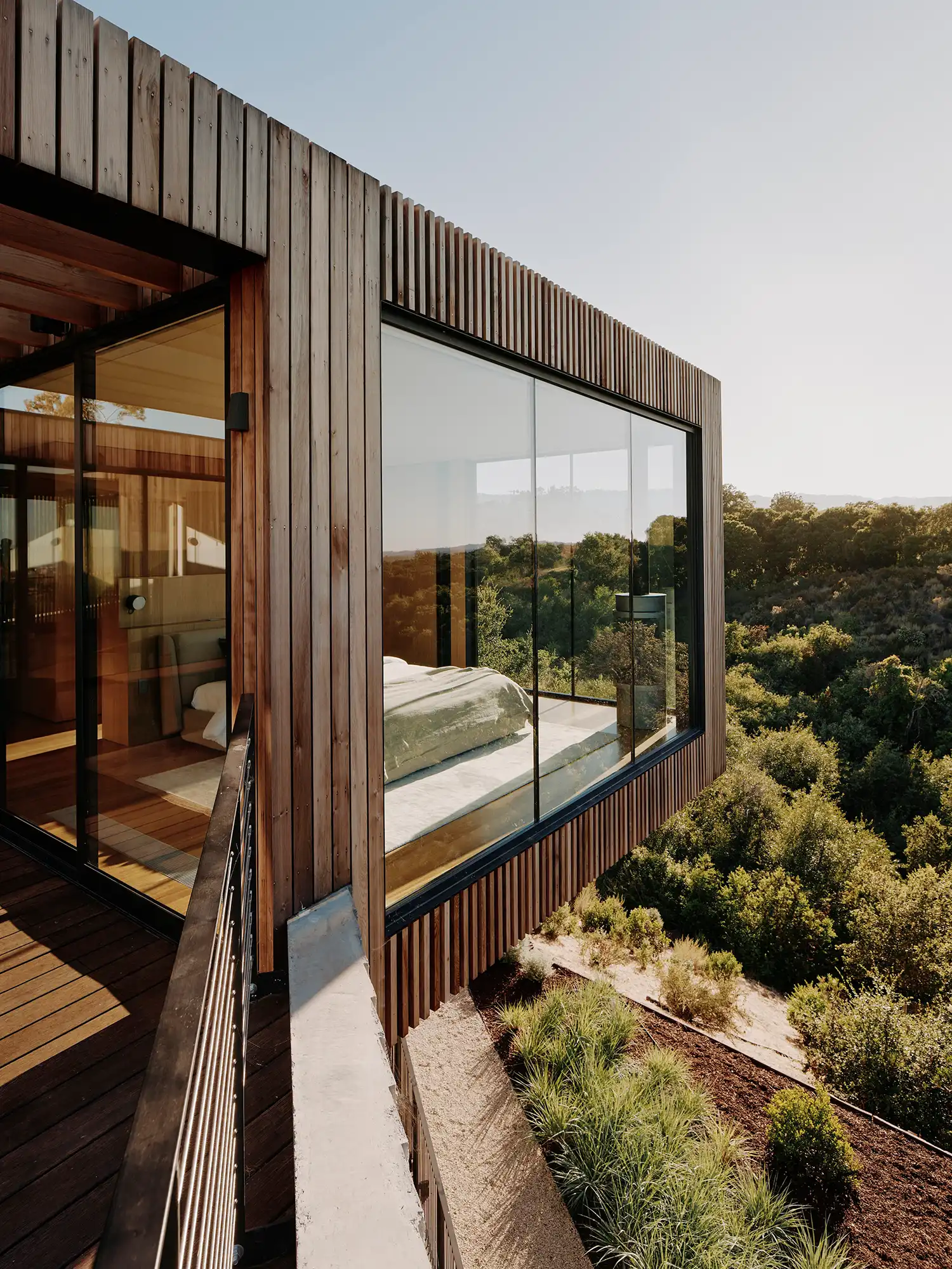 Detail of a cantilevered bedroom with glass walls overlooking an oak woodland.