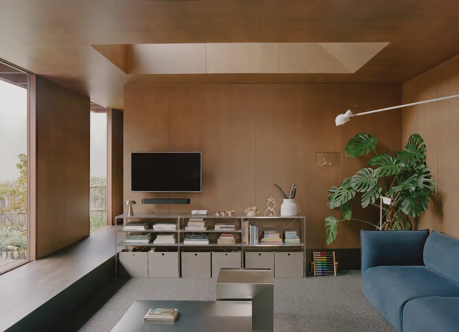 Interior view of sunken living room featuring earthy bronze walls, a blue sofa, and a large skylight.
