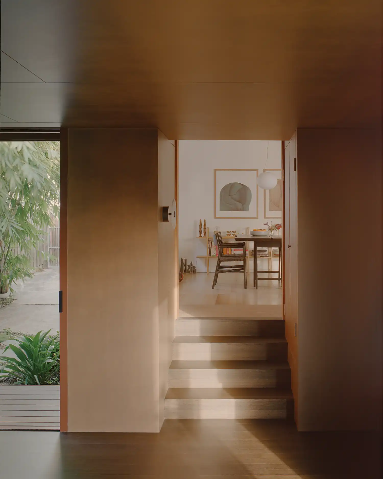 Transition space looking from the earthy addition towards the light-colored, renovated dining area of the original house.