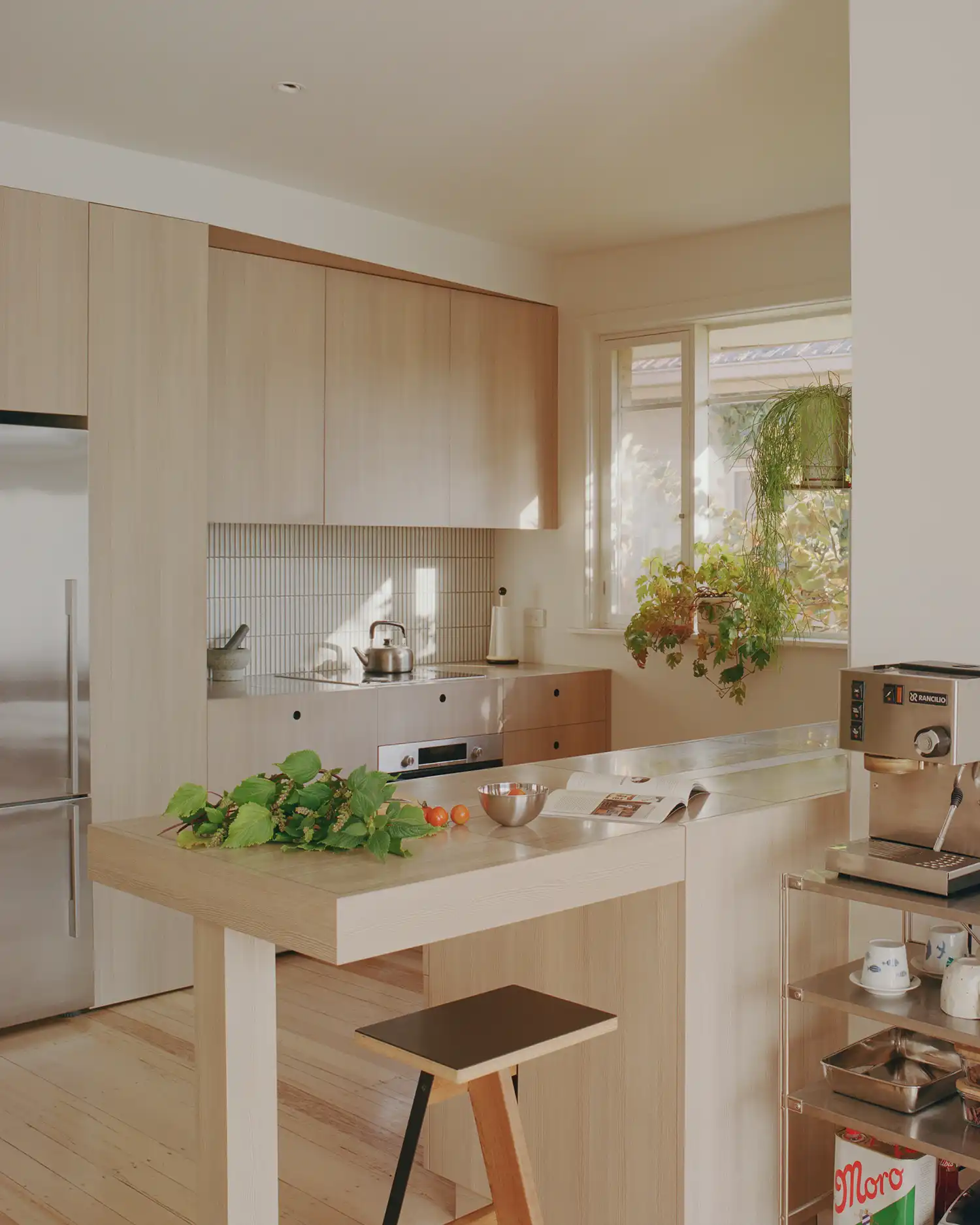Renovated kitchen with light timber cabinetry and stainless steel countertops in Cascade House.