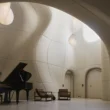 musician playing a grand piano in a white, organic-shaped room with curved GFRC walls.