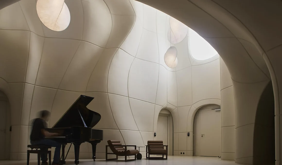 musician playing a grand piano in a white, organic-shaped room with curved GFRC walls.