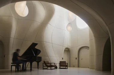 musician playing a grand piano in a white, organic-shaped room with curved GFRC walls.