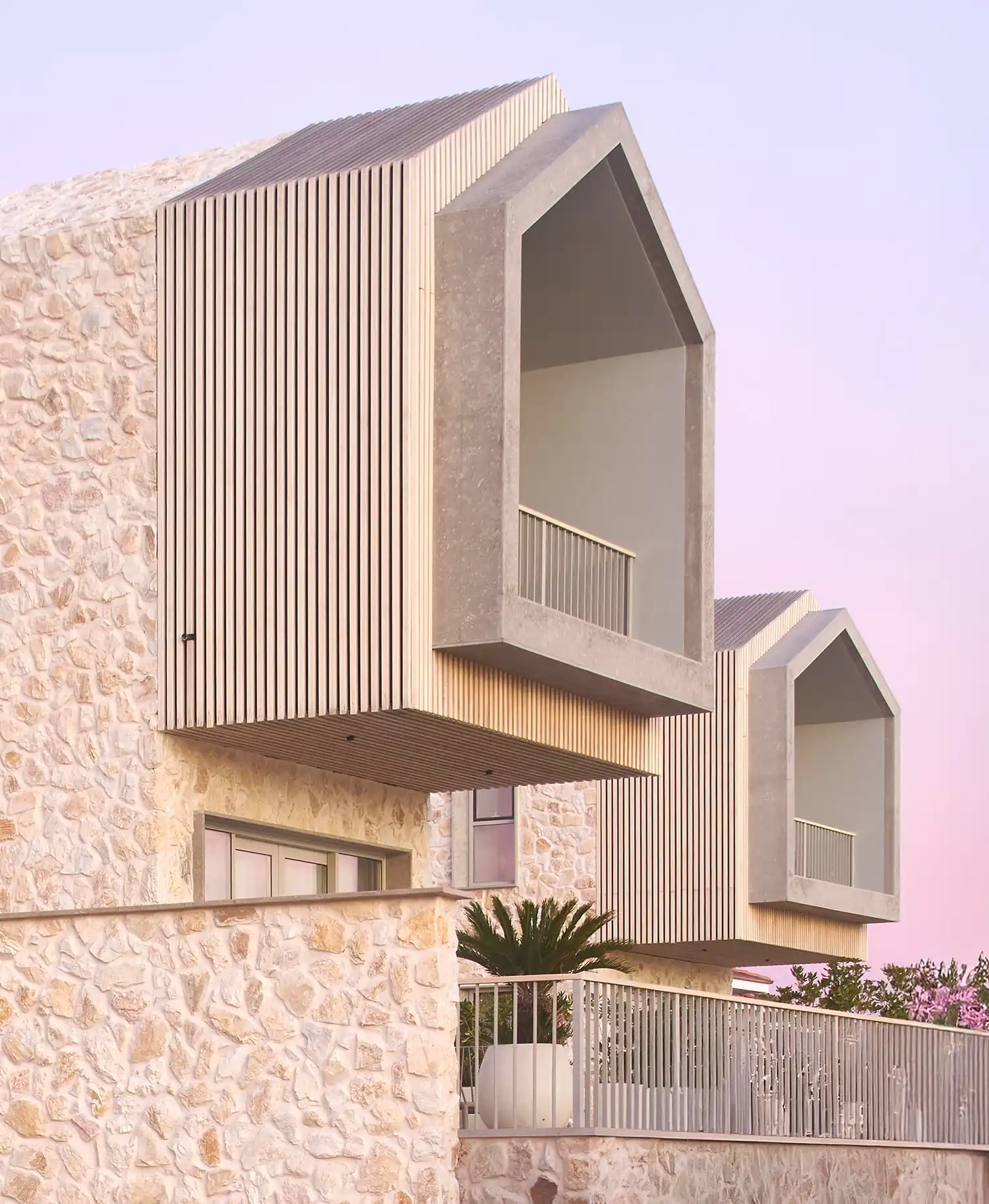 Close-up of gabled volumes with timber slats and stone masonry on a Cunda residence.