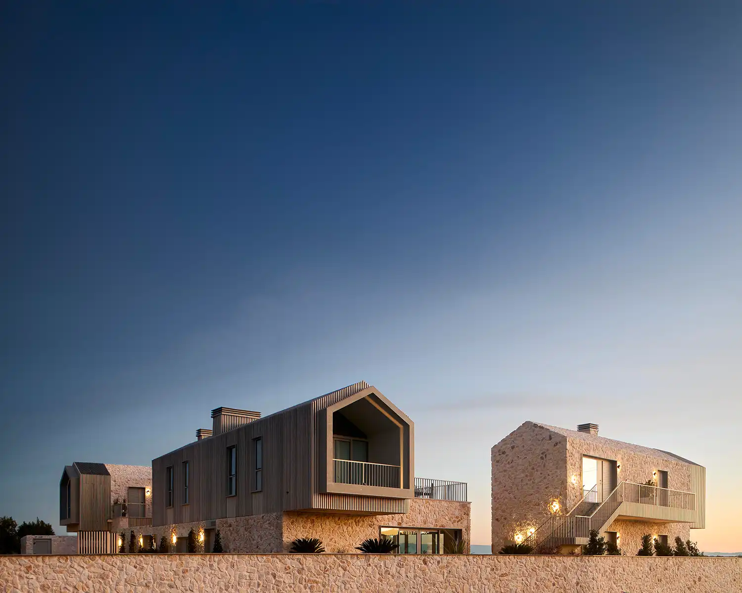 Wide view of several stone and timber buildings of the Pur complex at dusk.