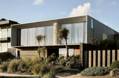 Exterior view of Coastal House by Splinter Society featuring a cantilevered concrete upper floor and recycled timber base.