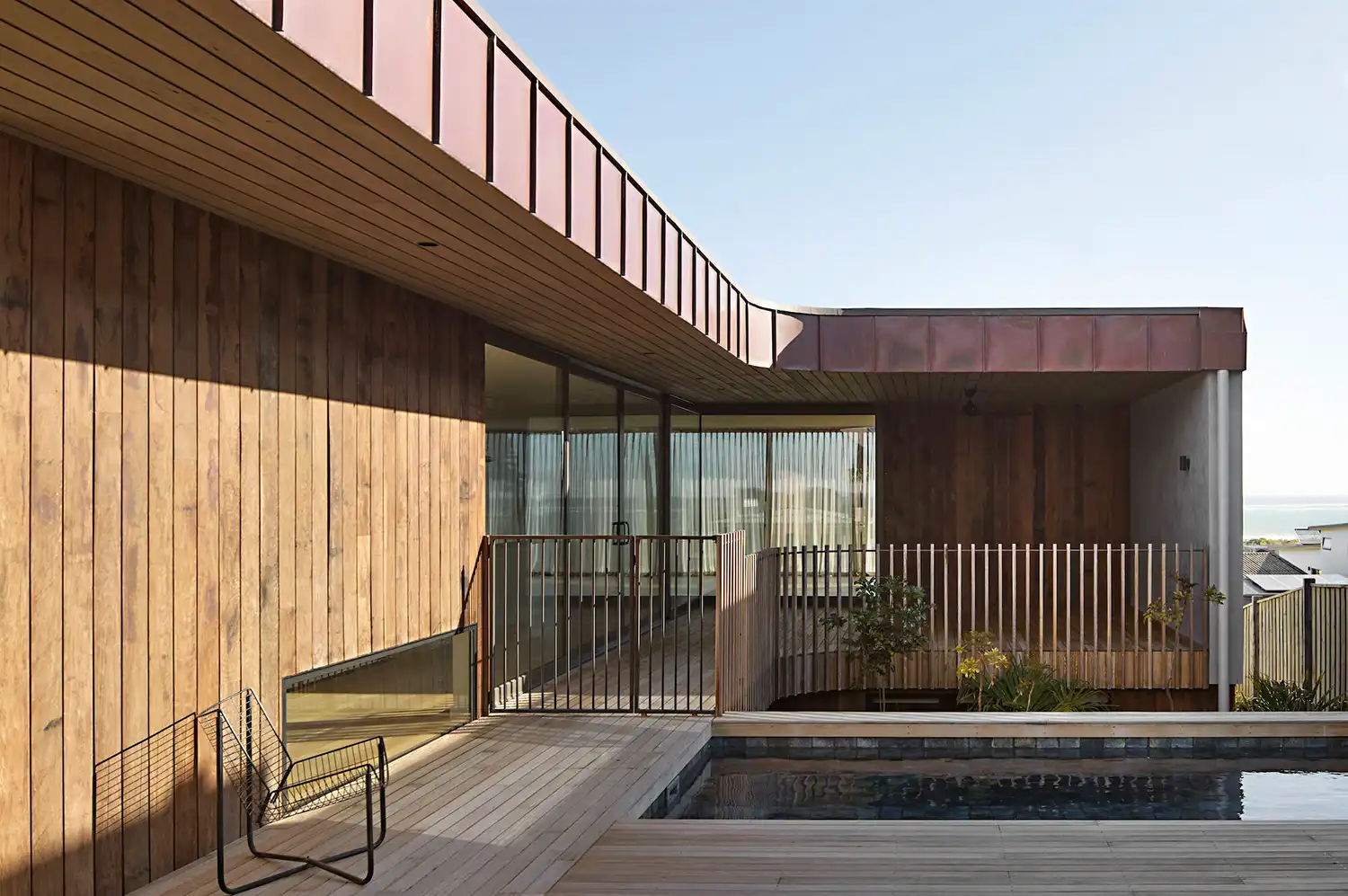 Internal courtyard with a pool pavilion featuring naturally patinated copper cladding and timber decking.