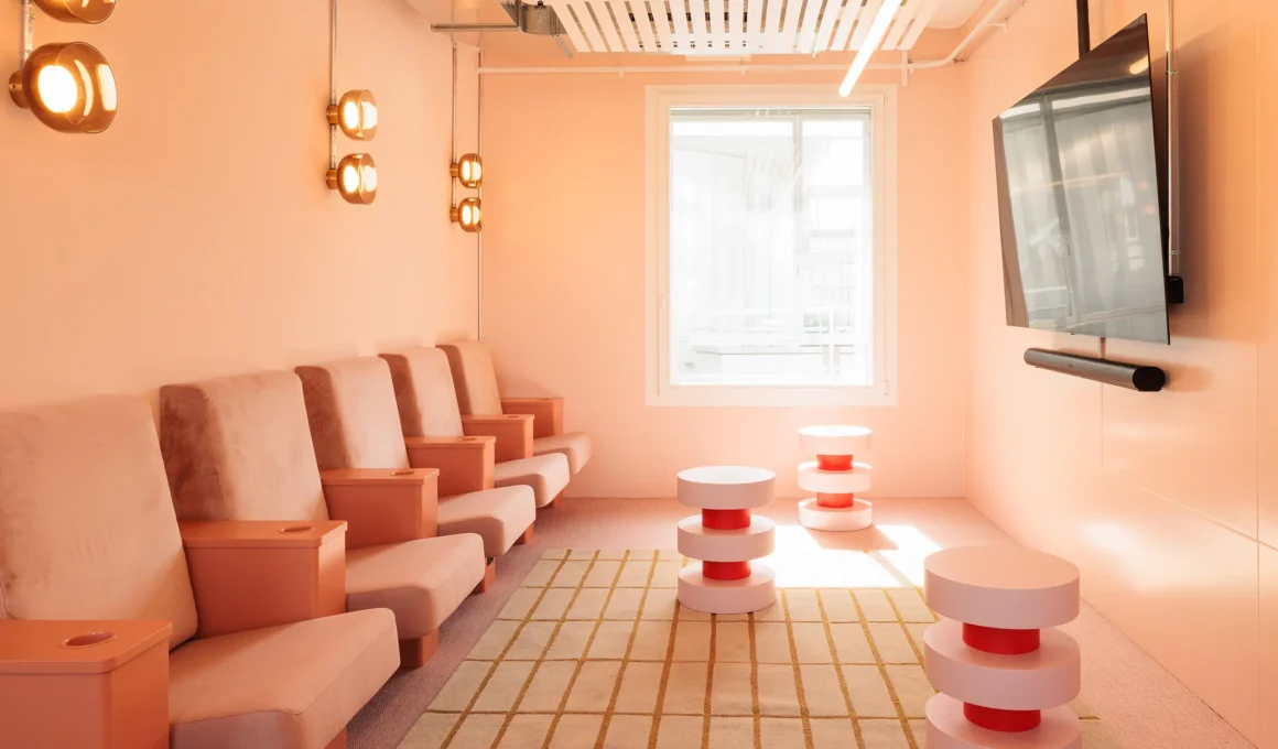 A row of peach-colored cinema seats with integrated cup holders in a modern HeadsQuarter meeting room, designed by Studio Aisslinger.