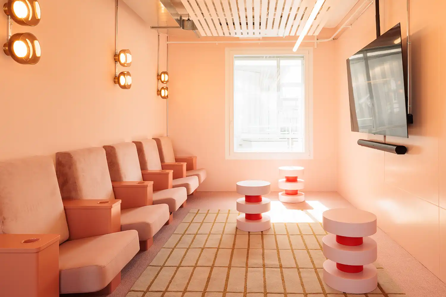 Peach-toned cinema room with tiered seating and wall-mounted lighting