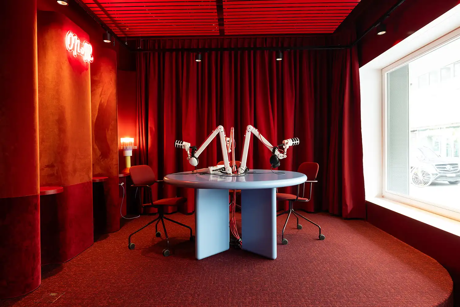 Red monochromatic podcast studio with professional microphones and velvet curtains