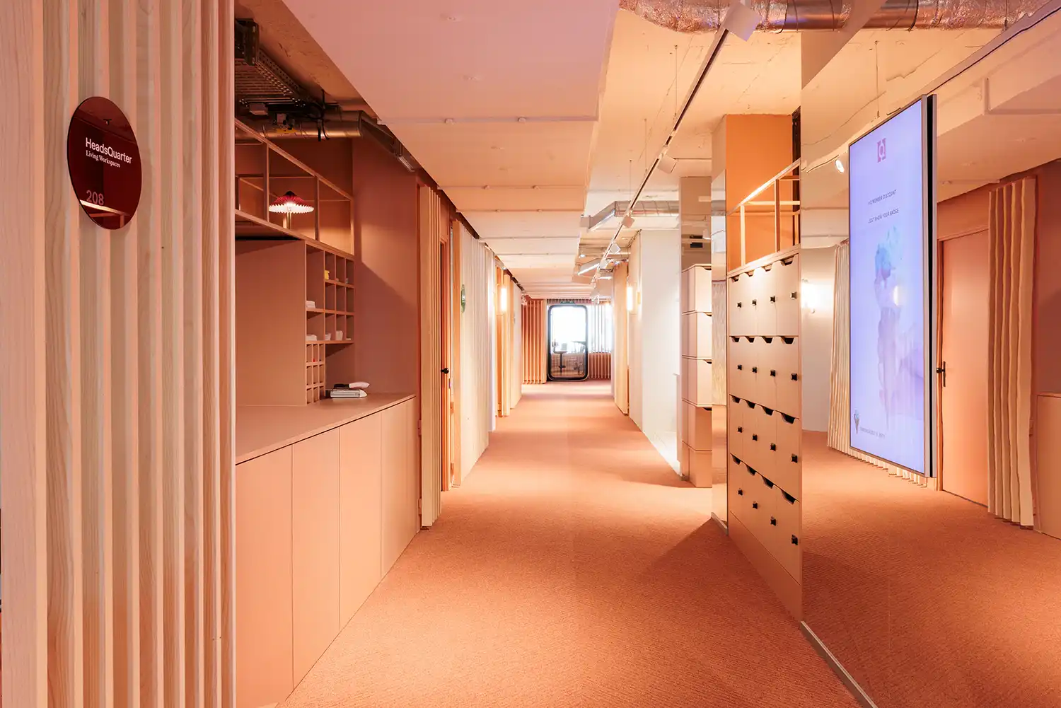 Perspective view of a peach-colored corridor with integrated lockers and mirrors