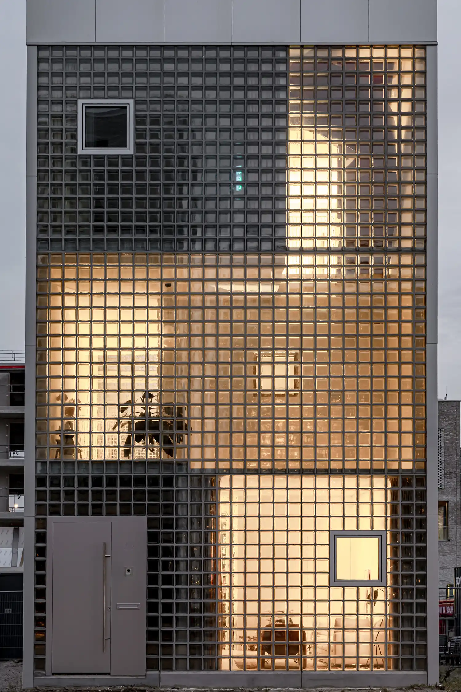 Detail of the glass block facade of Light House glowing from interior lights at night.